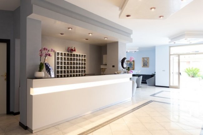 Reception moderna con bancone bianco.