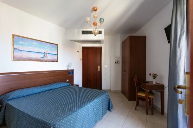 Stanza d'hotel con letto matrimoniale e arredi in legno.