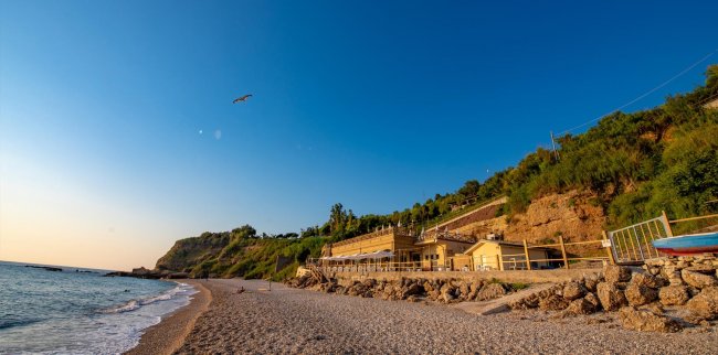 Spiaggia con case e scogliera al tramonto.