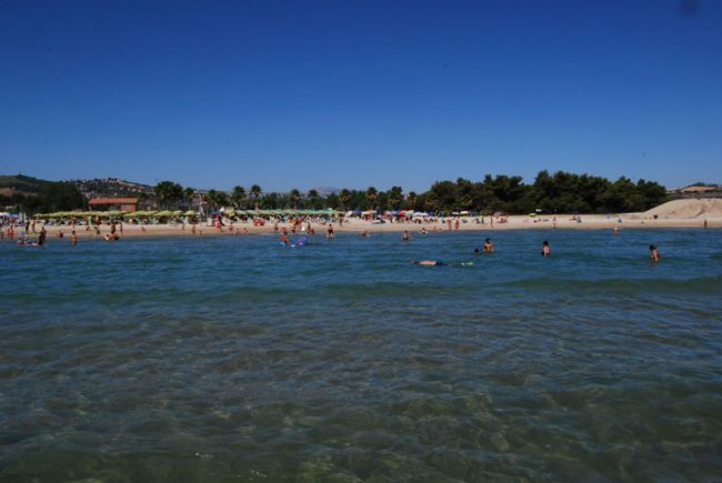 Spiaggia affollata con bagnanti in acqua.