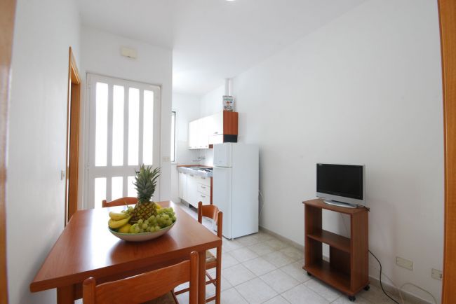 Cucina con tavolo, frutta e TV su carrello.