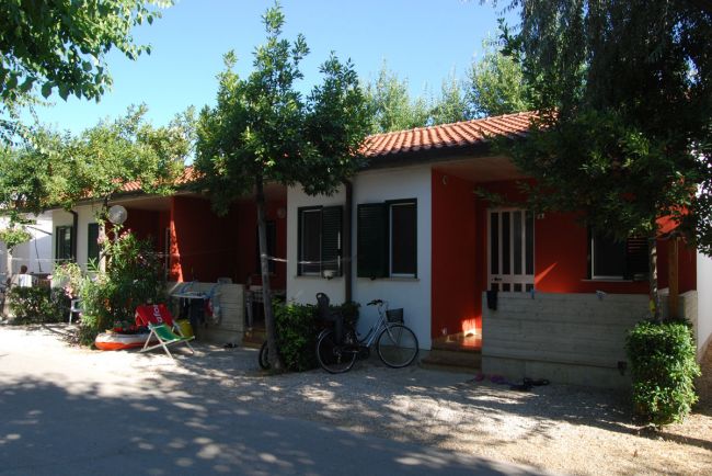 Casetta rossa con veranda, bici e piante.