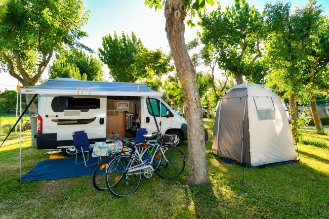 Camper e tenda in un'area verde con biciclette.