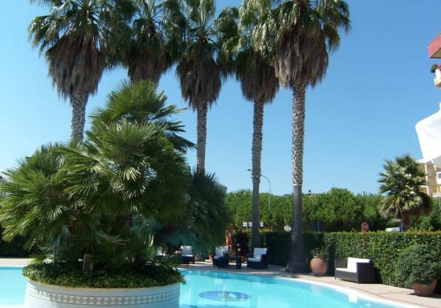Piscina con palme e vegetazione rigogliosa intorno.