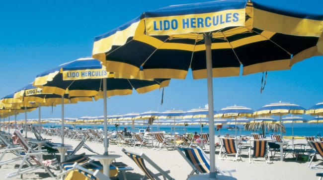 Ombrelloni blu e gialli allineati su una spiaggia.