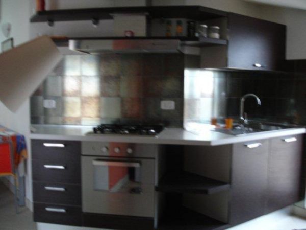 Cucina moderna con mobili scuri, piano cottura e lavello in acciaio.