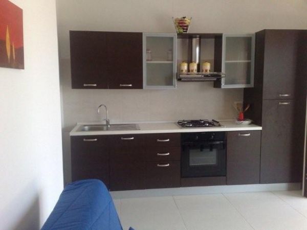 Una cucina moderna con mobili scuri, un forno e un lavandino.