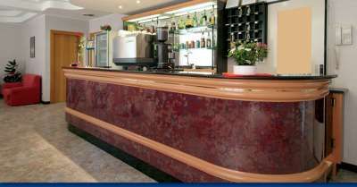 Bancone da bar elegante in legno scuro con bottiglie e tazze sullo sfondo.