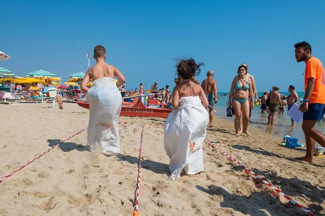 Corsa nei sacchi su una spiaggia affollata.