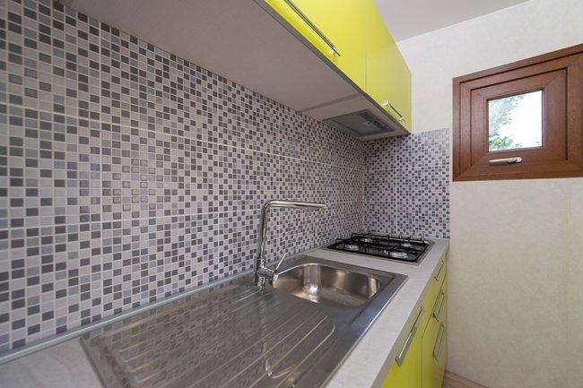 Cucina con mosaico e mobili gialli.