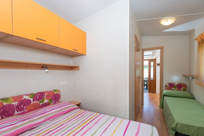 Camera con letto matrimoniale e armadio arancione.