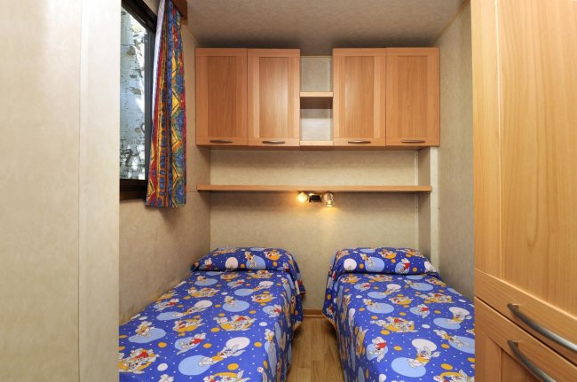 Cameretta con due letti singoli e copriletto blu a fantasia.