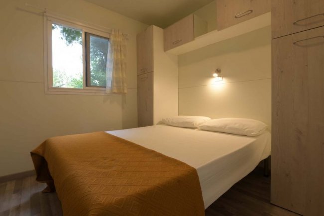 Camera da letto con letto matrimoniale e copriletto arancione.