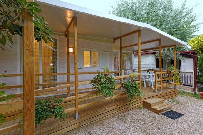 Casetta con veranda in legno e piante rampicanti.