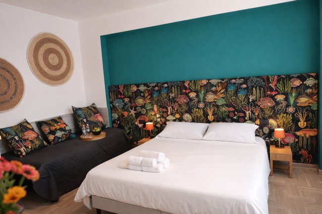 Camera da letto con testiera floreale e decorazioni murali.