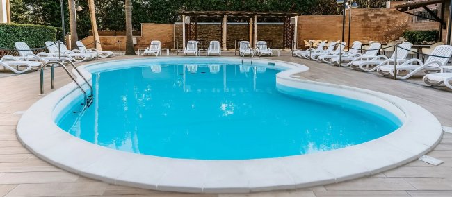 Piscina tonda, circondata da lettini bianchi.