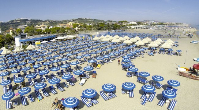 Spiaggia con ombrelloni blu e bianchi.